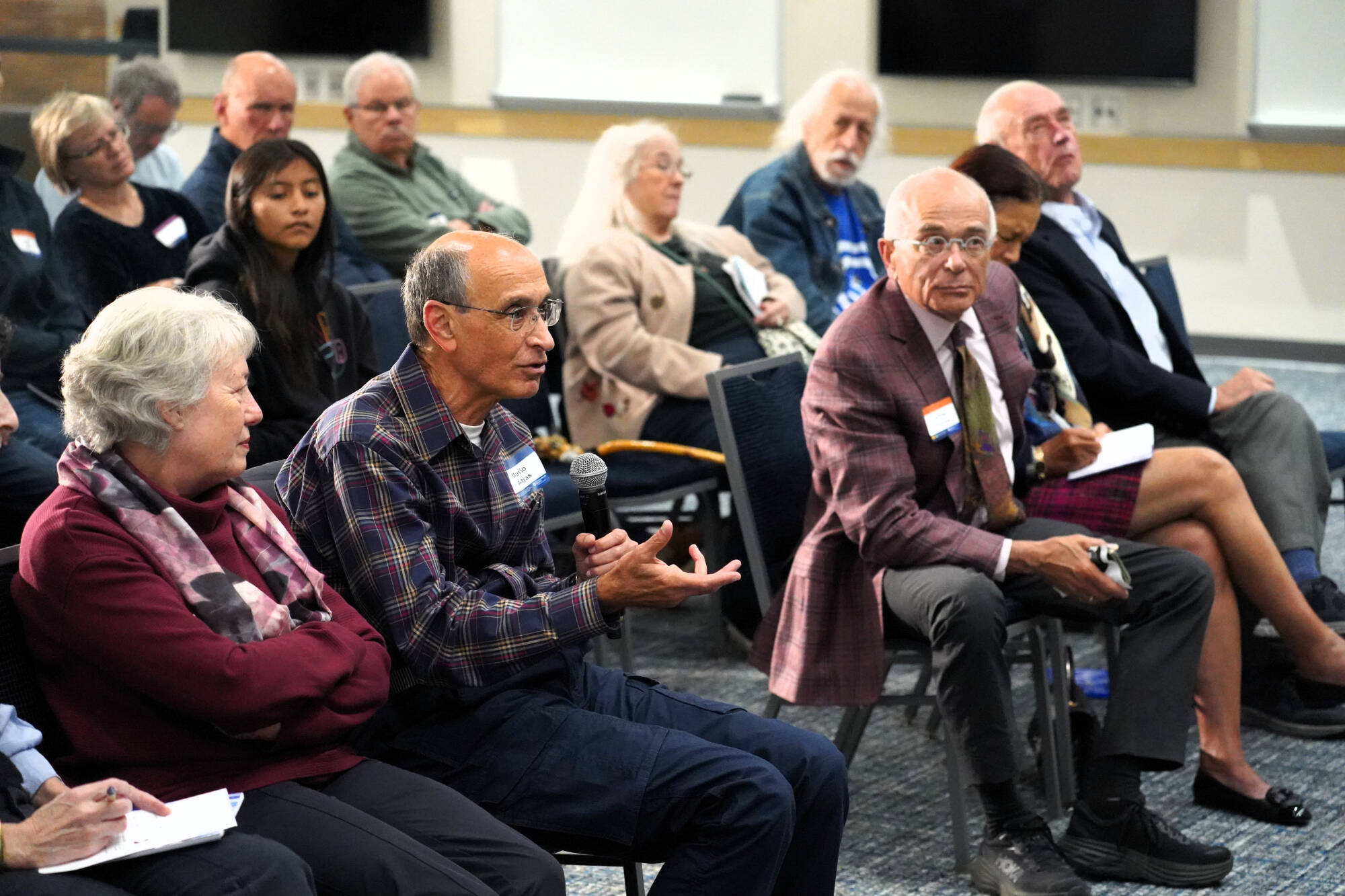An audience member asking a question with a microphone with others looking on.